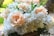 A bouquet of white and peach flowers in someone's hand