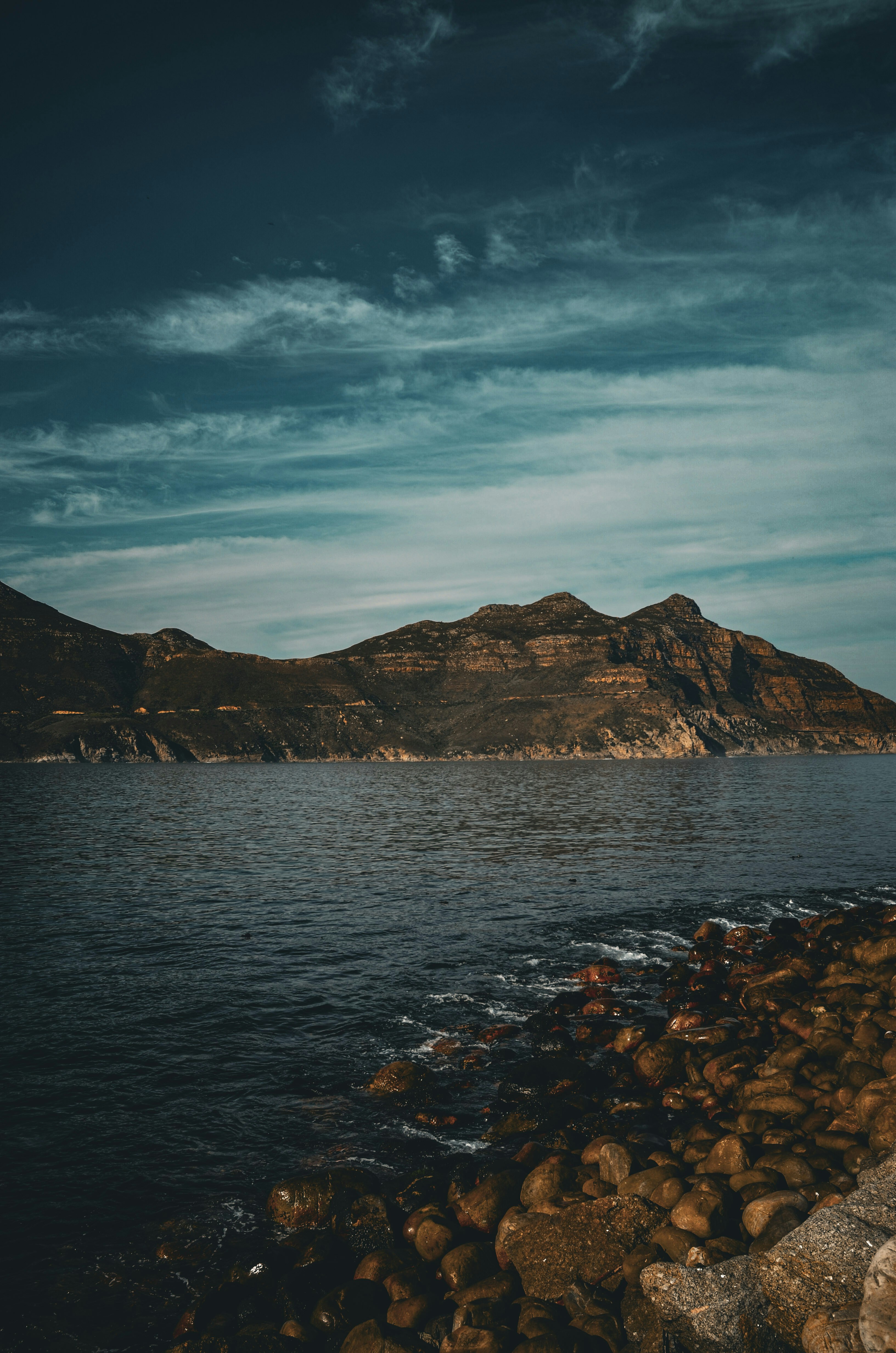 A person standing on a rocky shore next to a body of water
