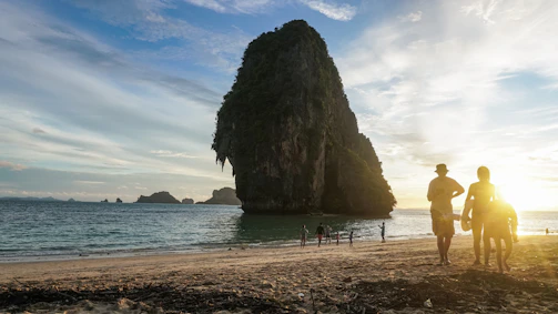 A couple of people standing on top of a sandy beach