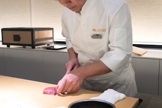 A man in a chef's uniform cuts a piece of meat