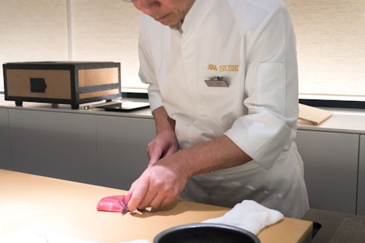 A man in a chef's uniform cuts a piece of meat