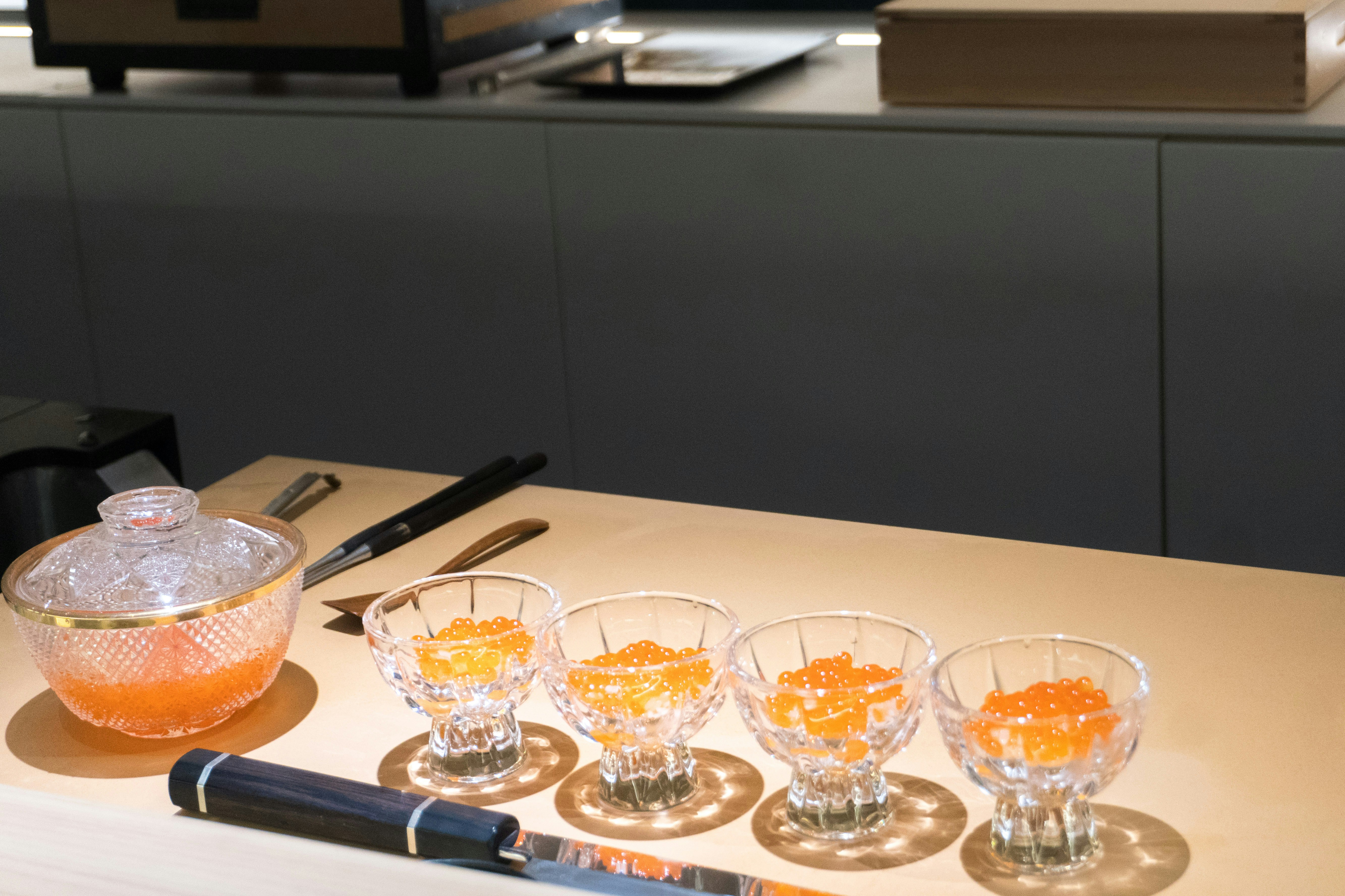 A table topped with glasses and a bowl of oranges