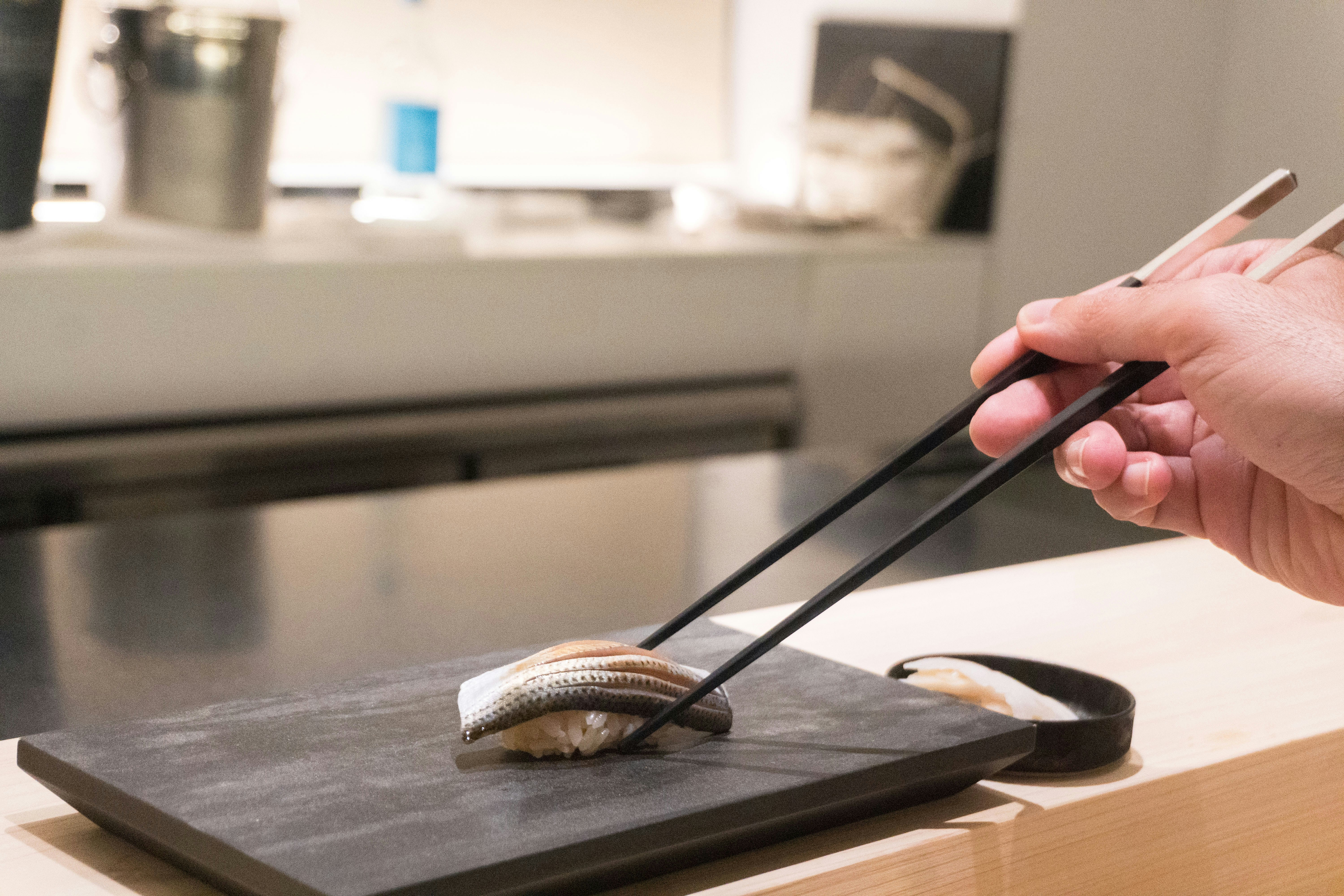 A person holding chopsticks over a piece of food