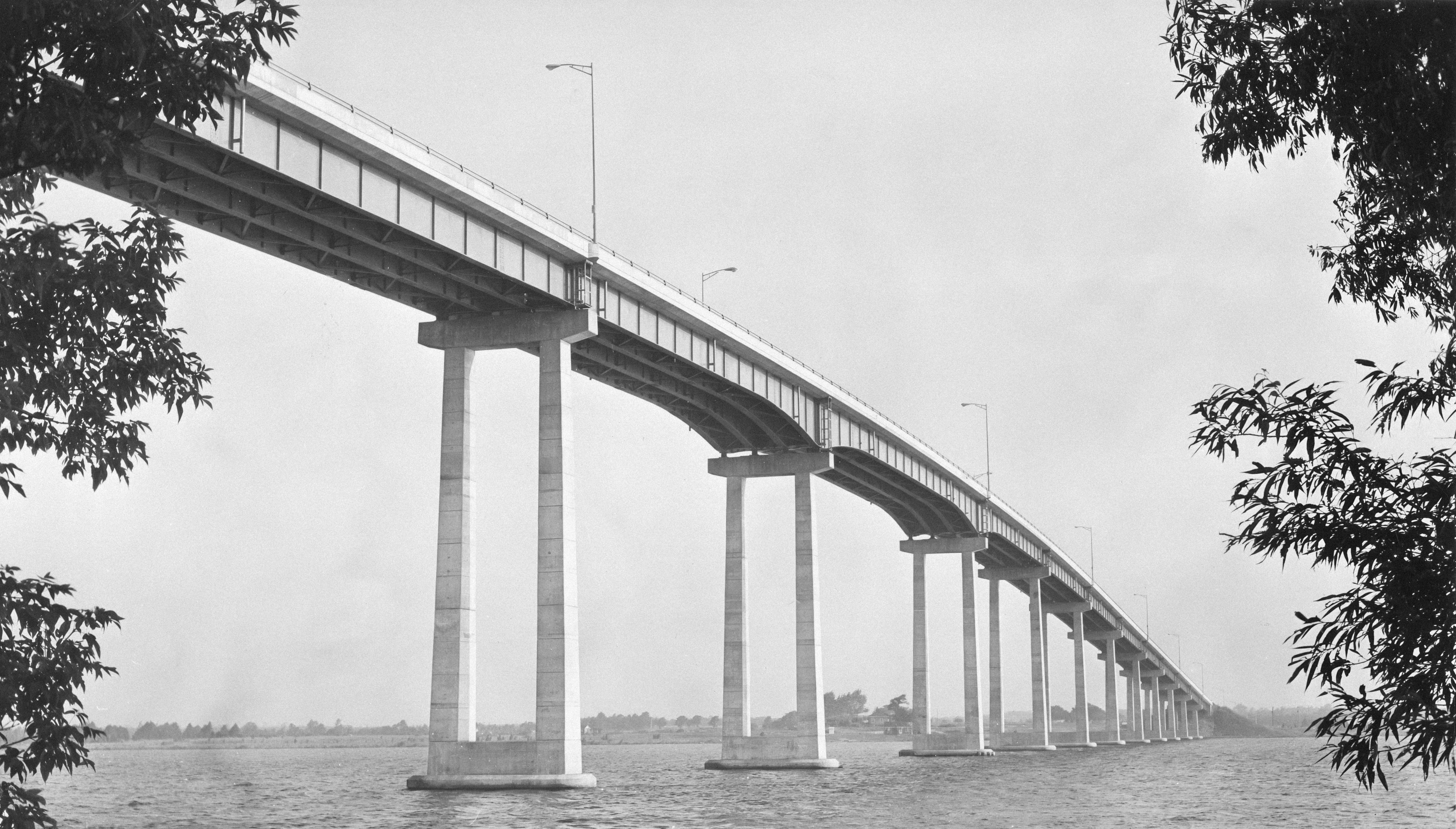 Un long pont en béton enjambe une eau calme.