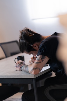 A person sitting at a table writing on a piece of paper