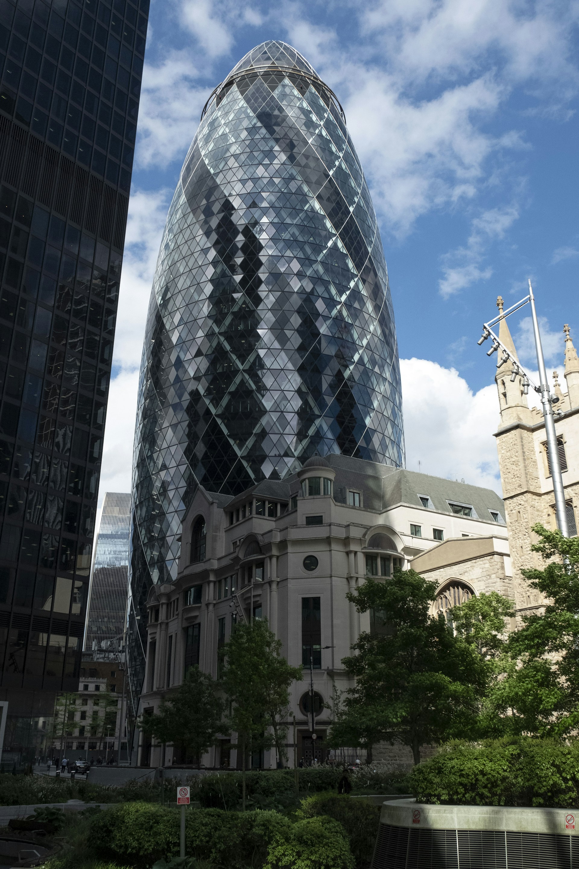 A very tall glass building next to other tall buildings