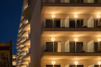 A tall building with many balconies lit up at night