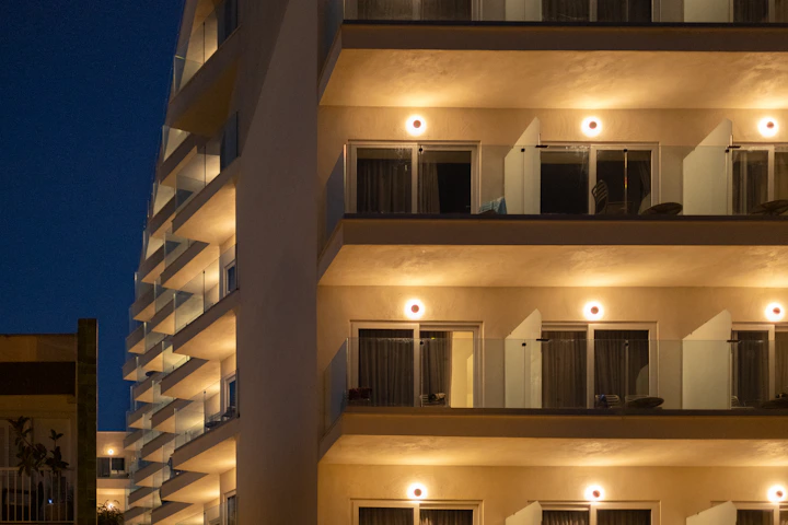 A tall building with many balconies lit up at night