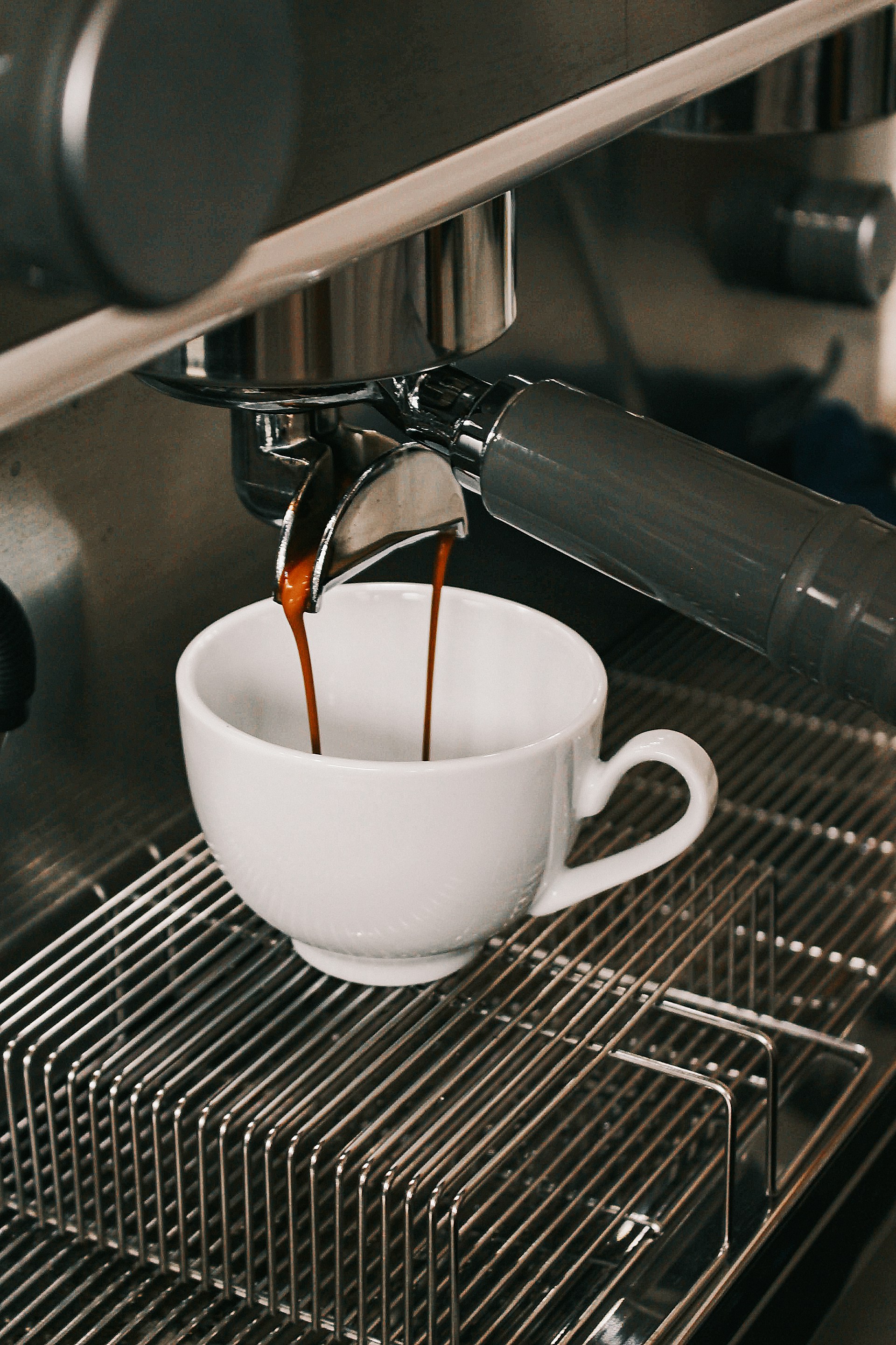 A cup of coffee being poured into a coffee machine