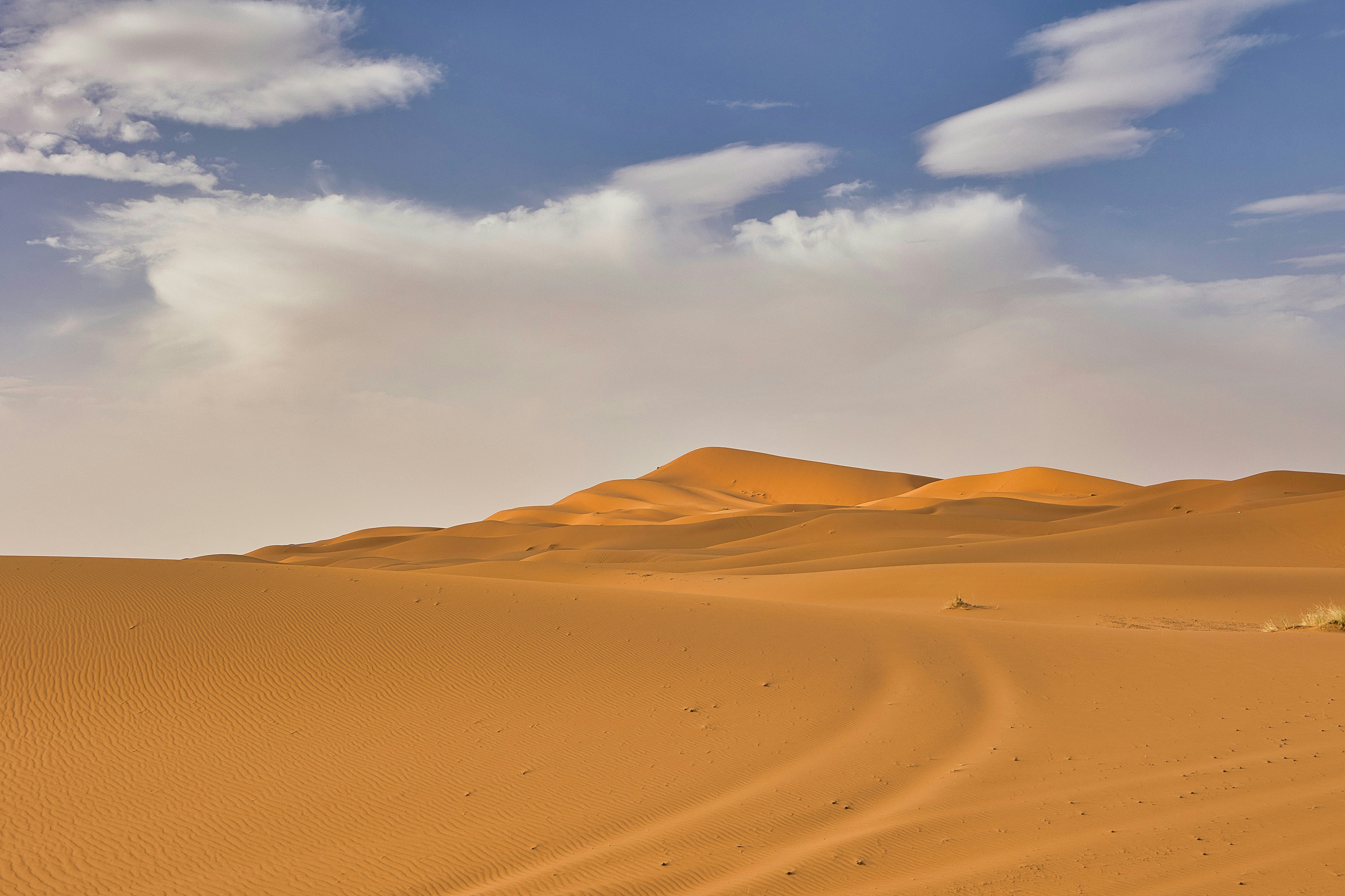 A desert landscape with sand dunes and clouds in the sky
