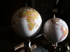 Two globes sitting on top of a wooden table