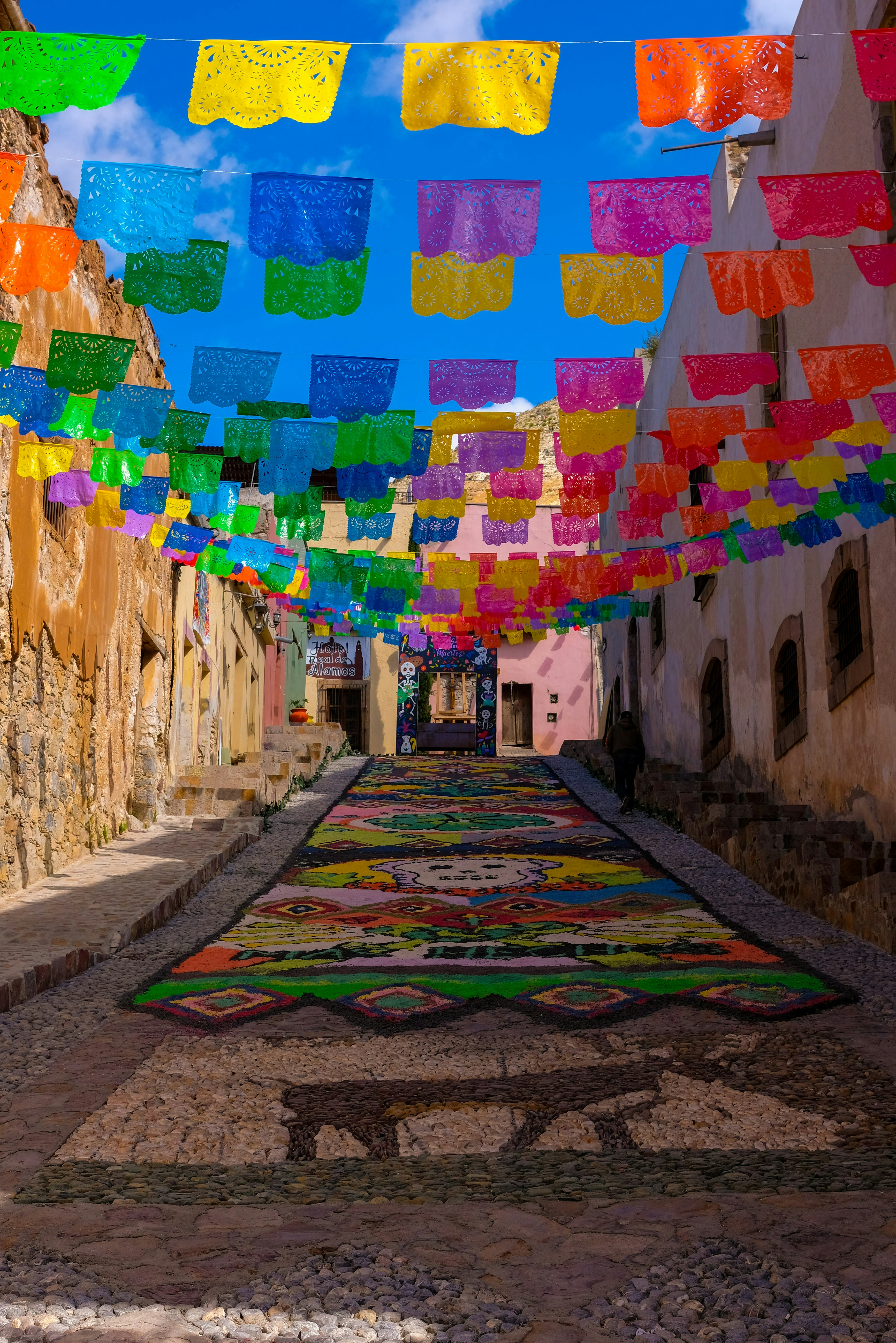 A street with a lot of colorful flags hanging from it's sides