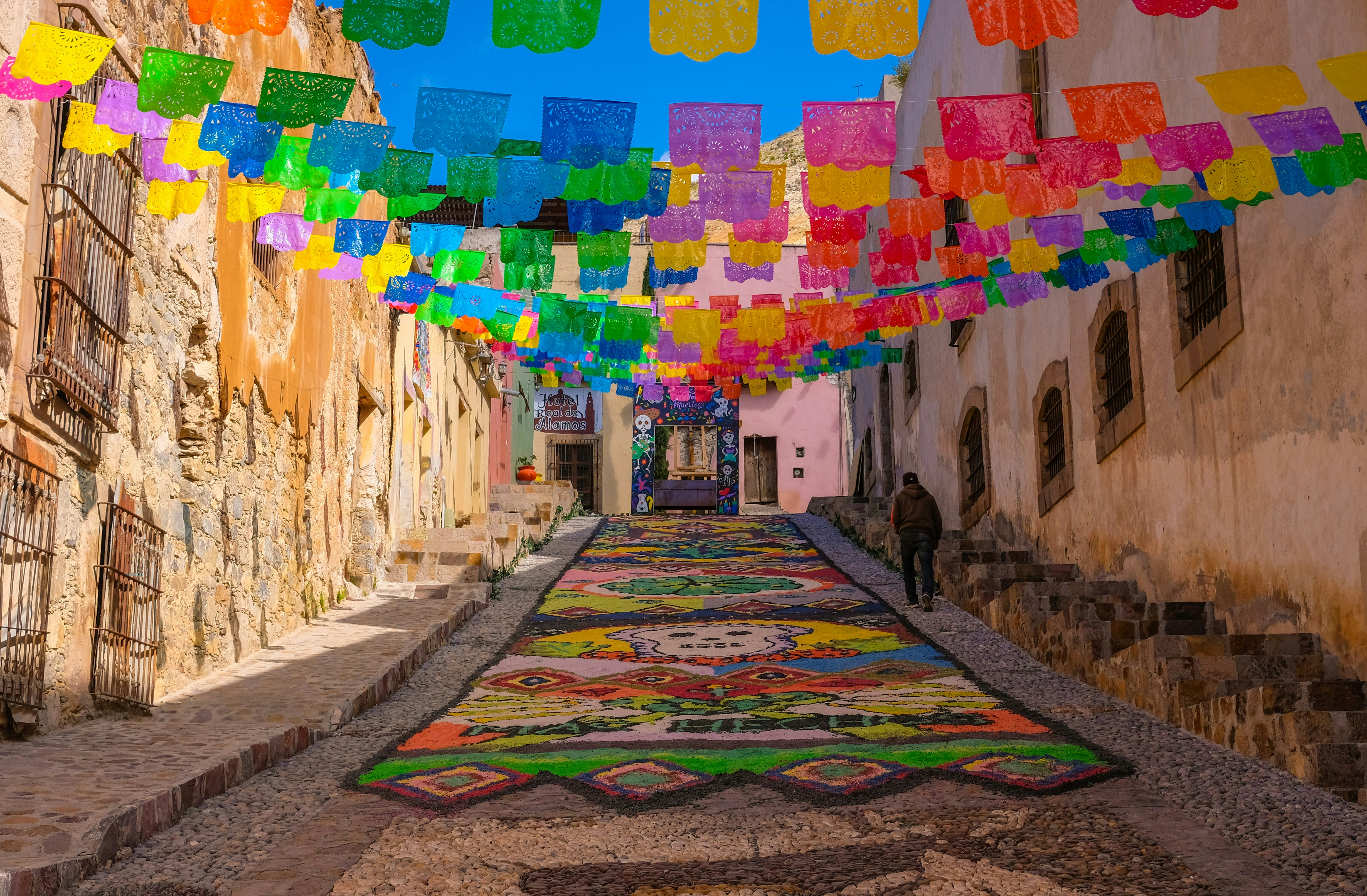 A street with a lot of colorful flags hanging from it's sides