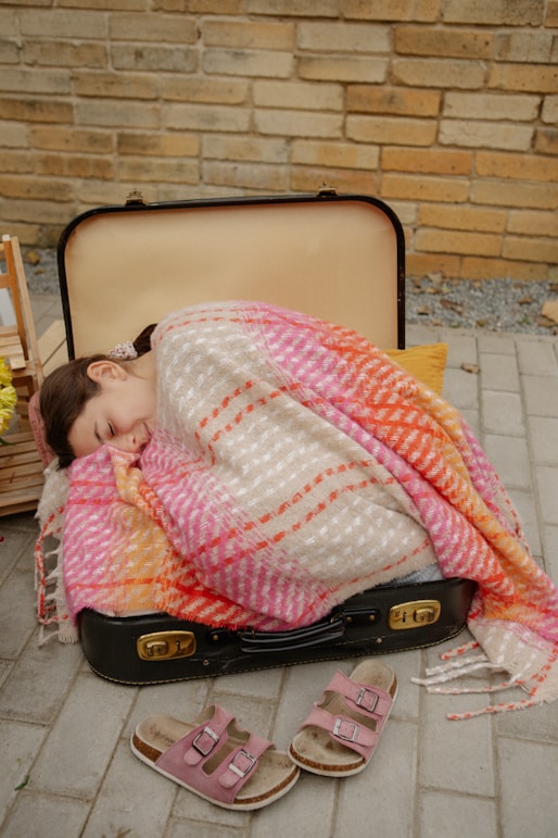 A woman sleeping in a suitcase on the ground