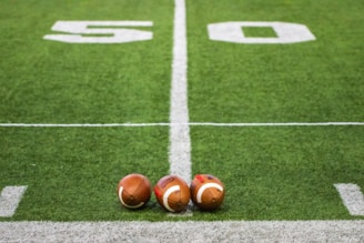 Three footballs sitting on a football field