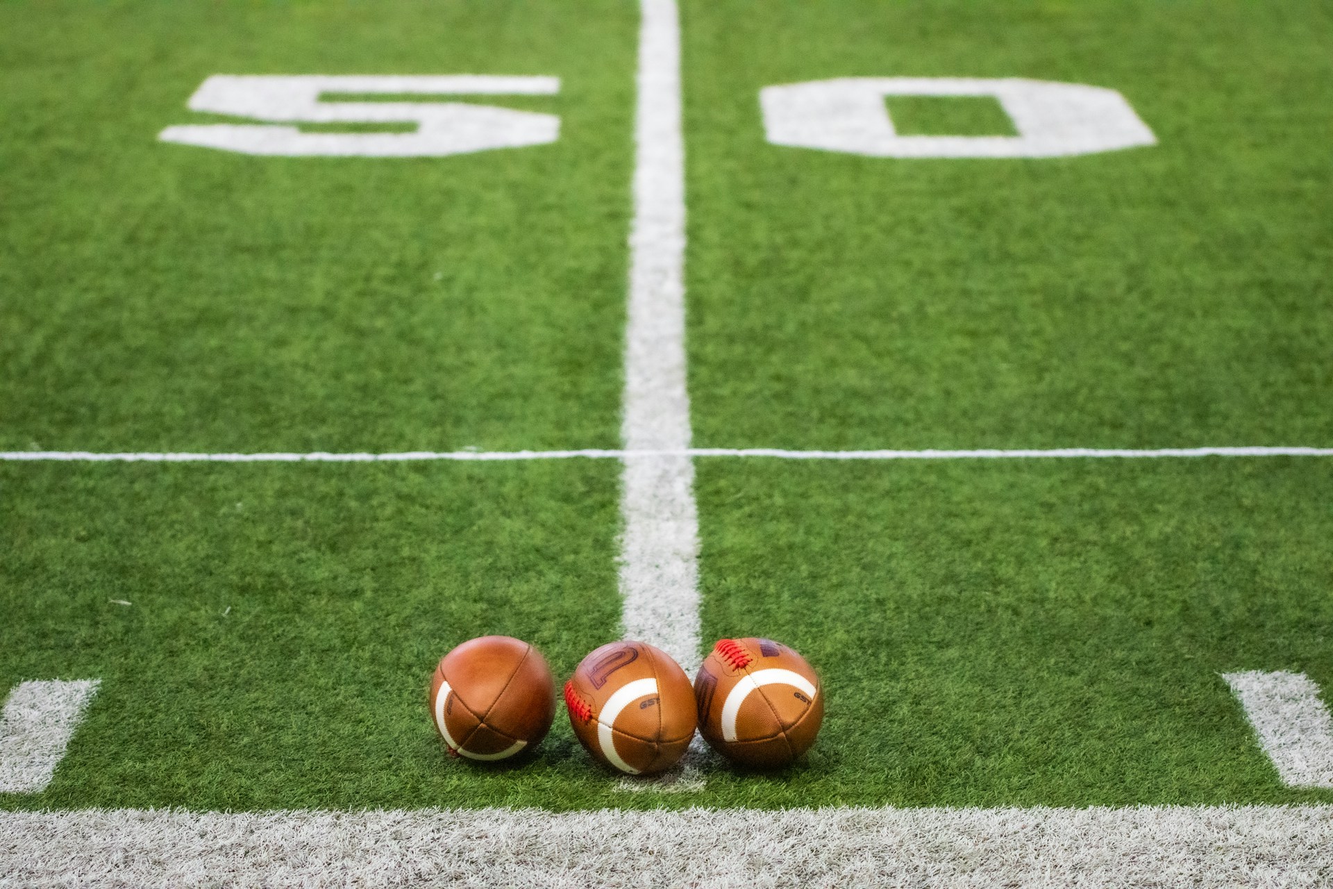 Three footballs sitting on a football field