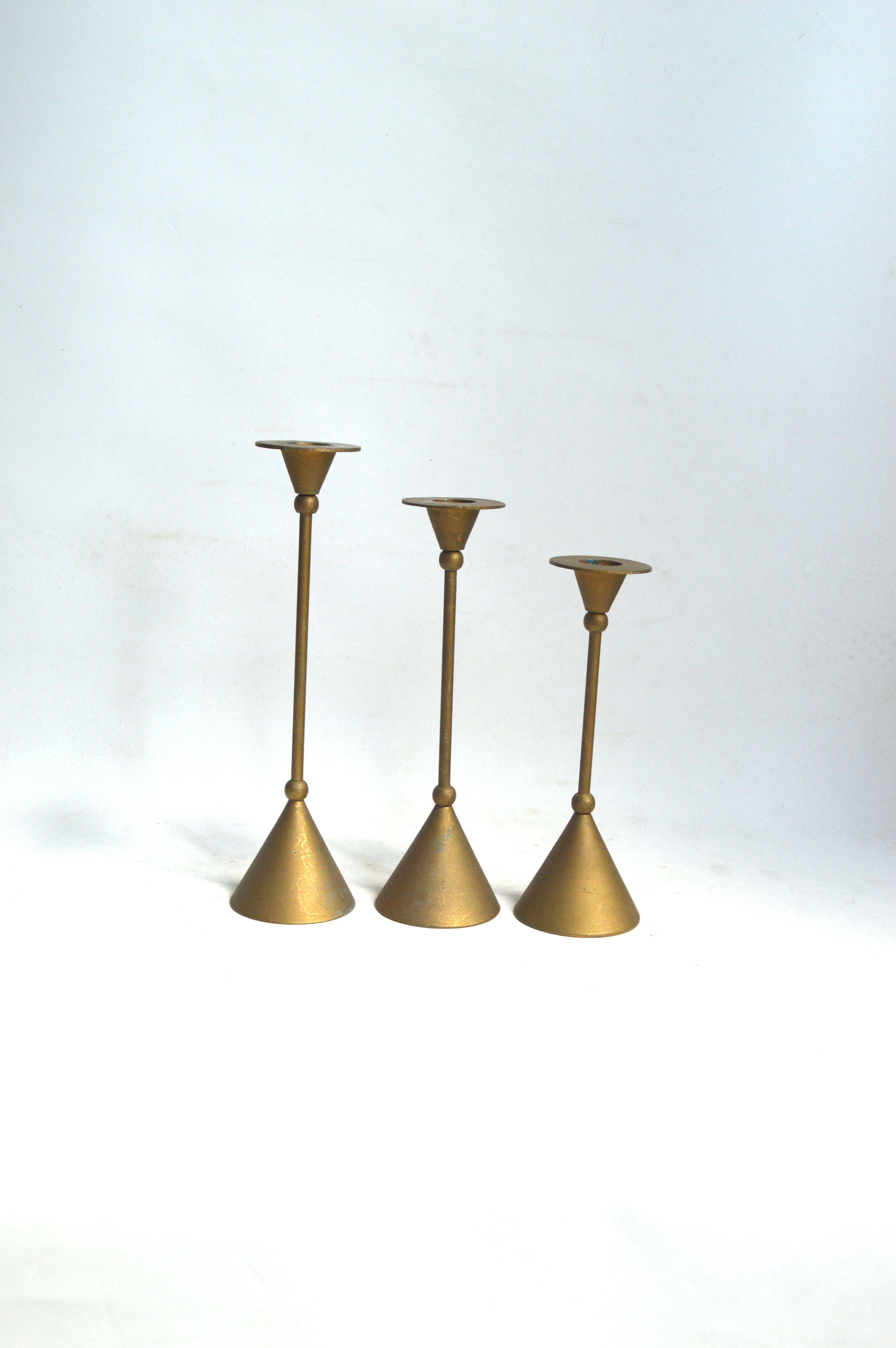 Tre candelabri in ottone su sfondo bianco