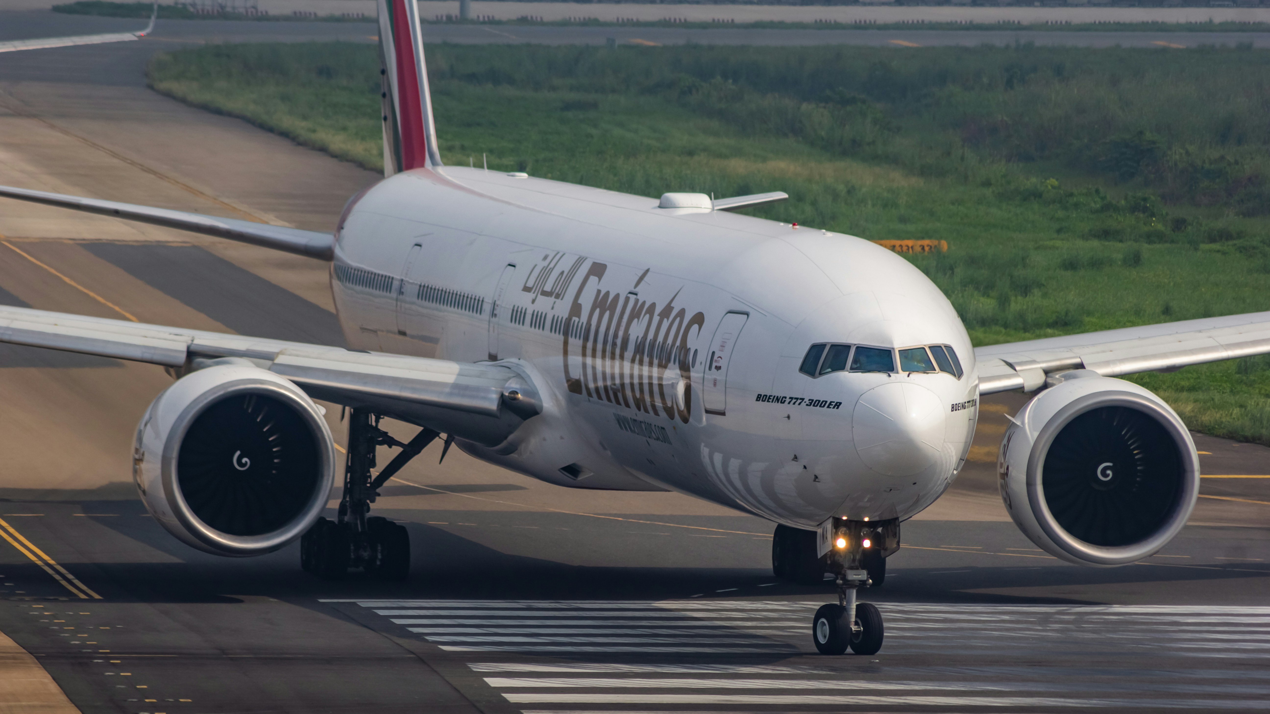 A large jetliner sitting on top of an airport runway, Emirates Boeing 777-300ER head pose.
