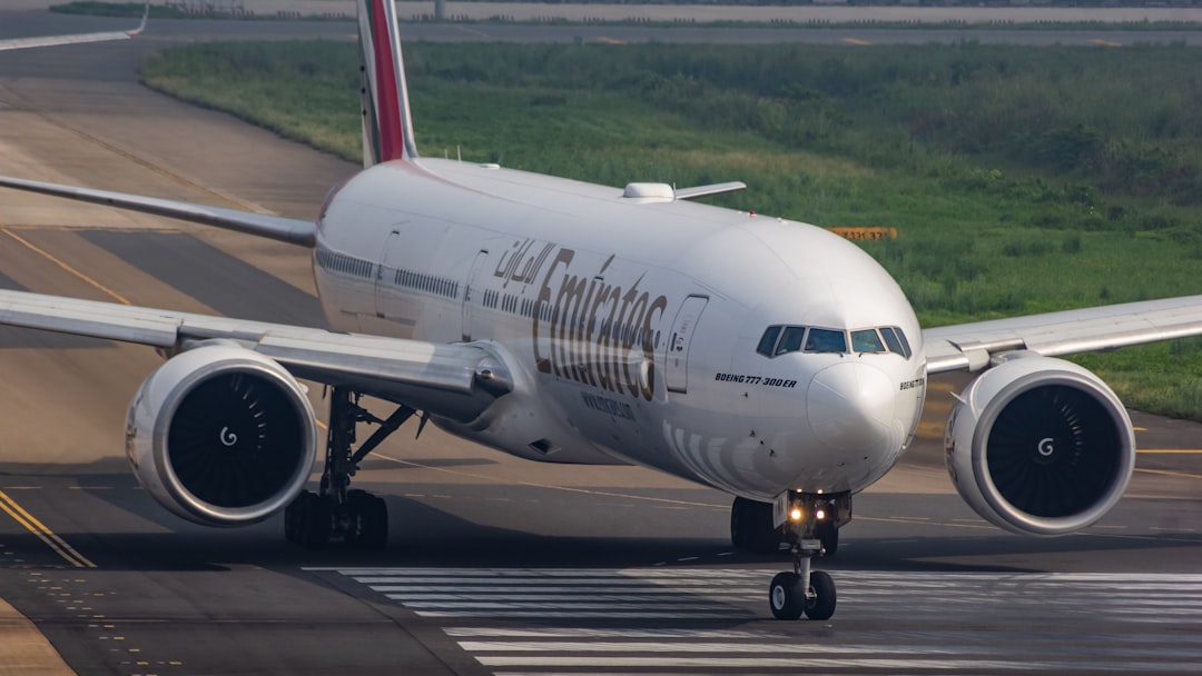 A large jetliner sitting on top of an airport runway, Emirates Boeing 777-300ER head pose.