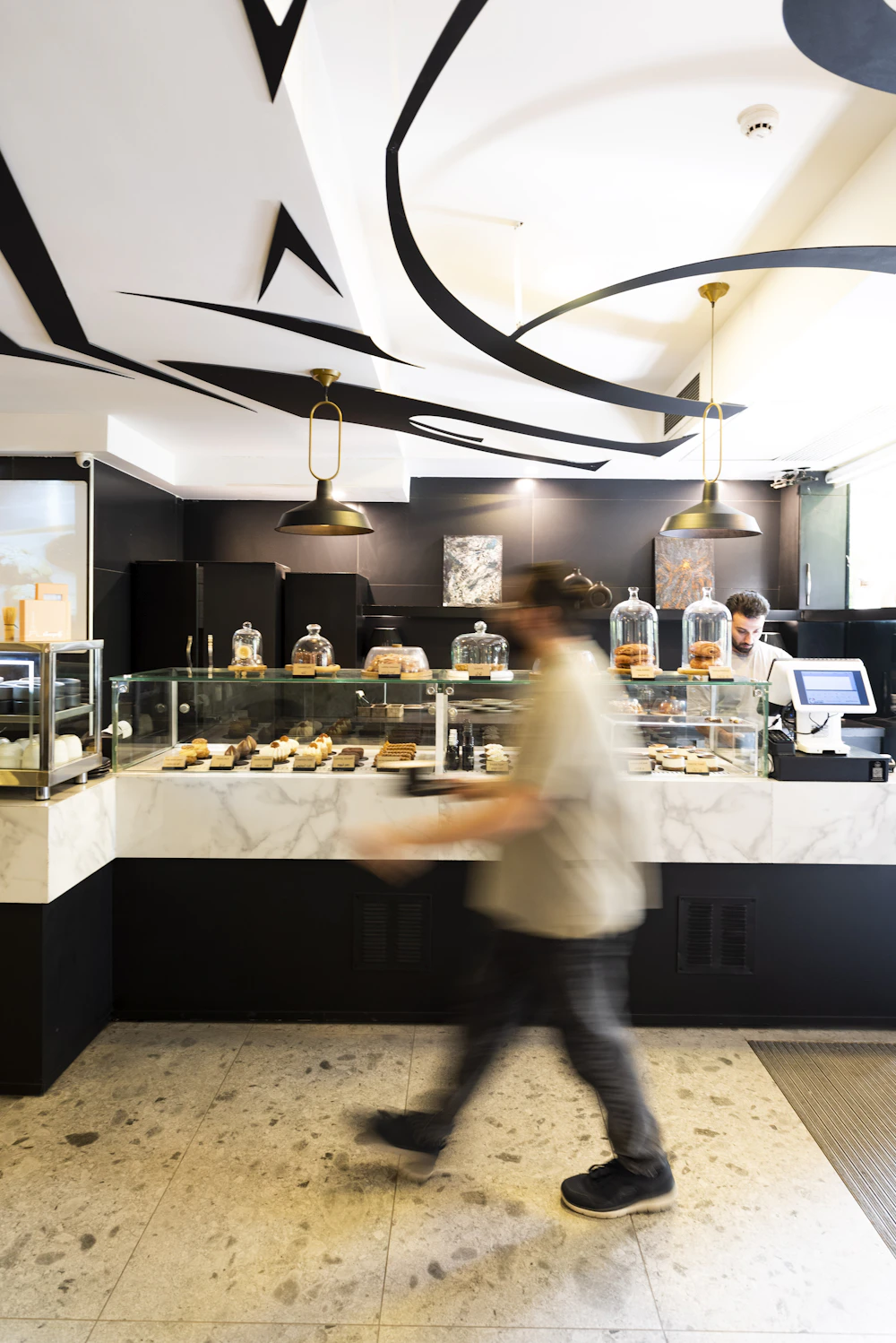 The interior of a bright bakery with a glass display case full of baked goods