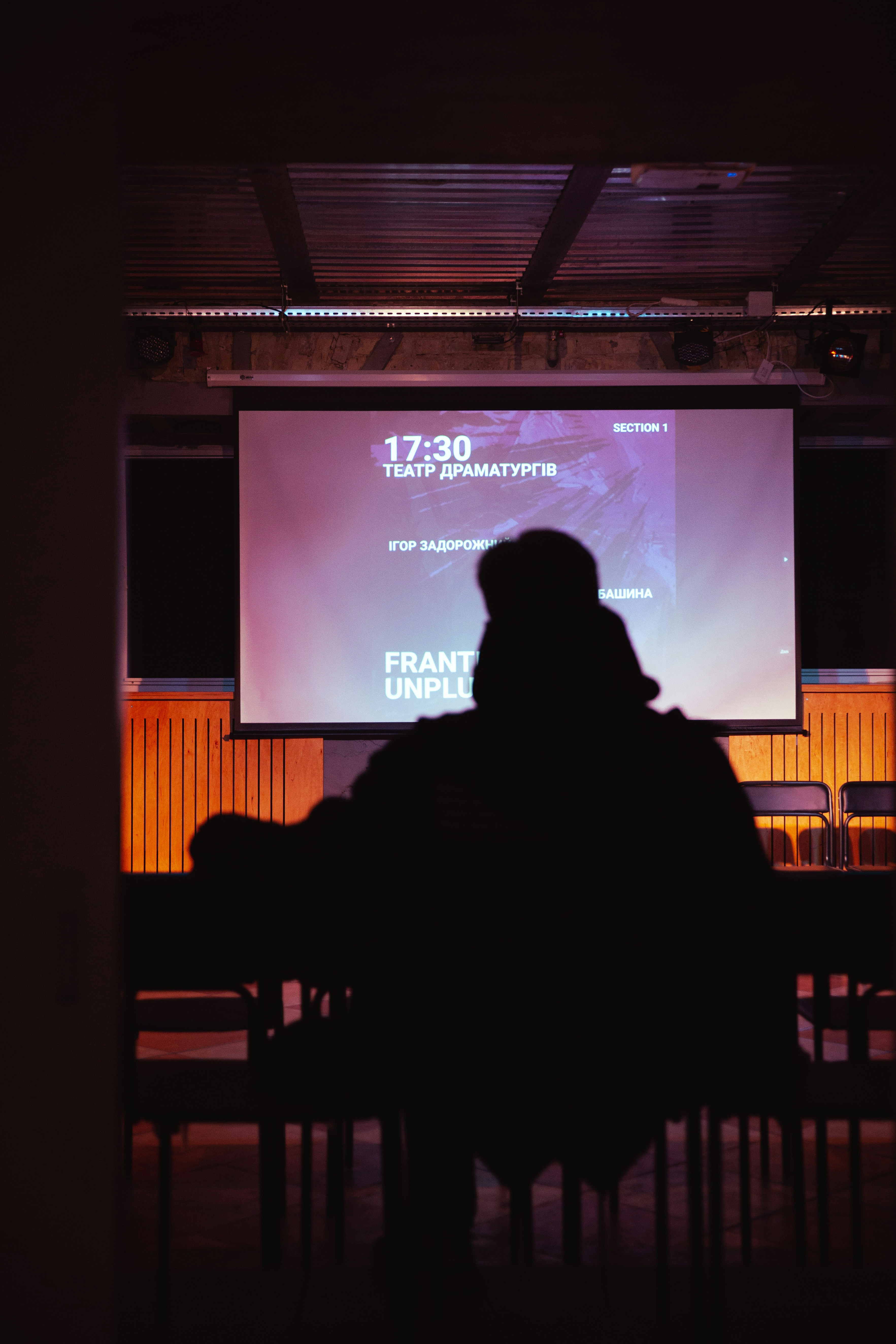A person sitting at a table in front of a projection screen