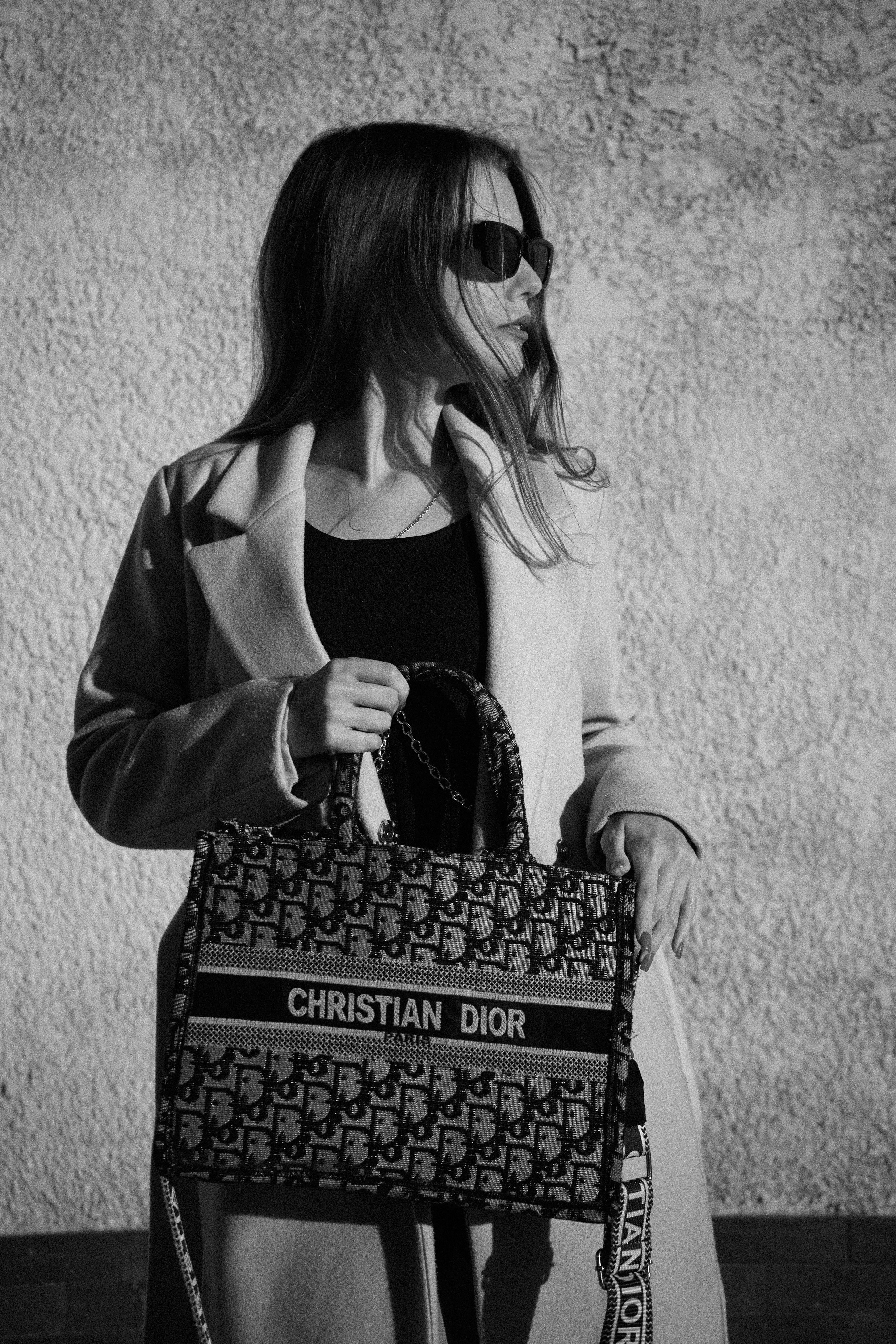 Une femme portant un sac à main debout devant un mur