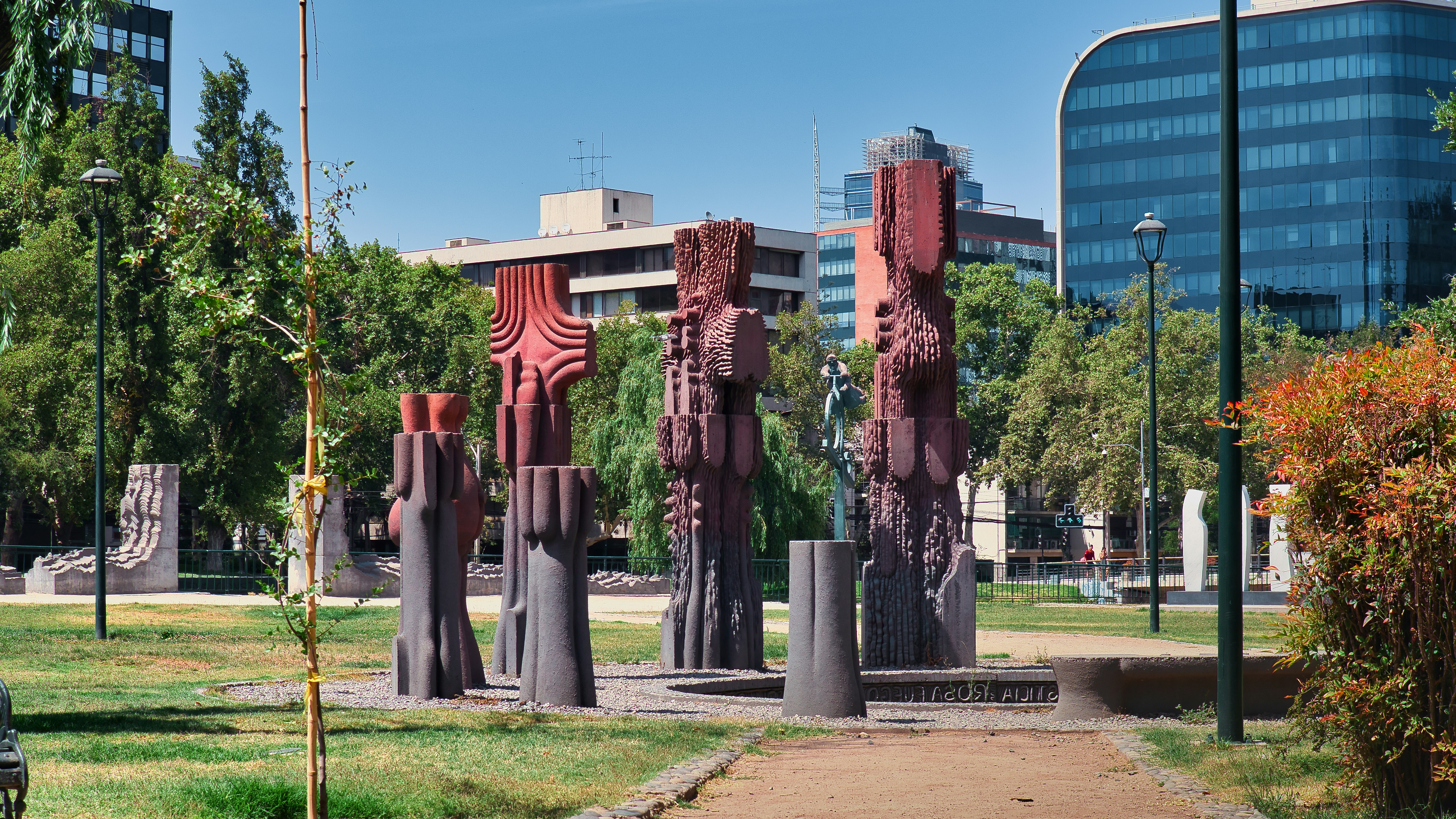 A group of statues in a park with buildings in the background