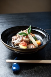 A bowl of food with chopsticks on a table
