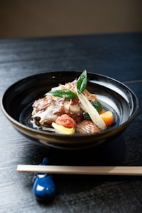 A bowl of food with chopsticks on a table