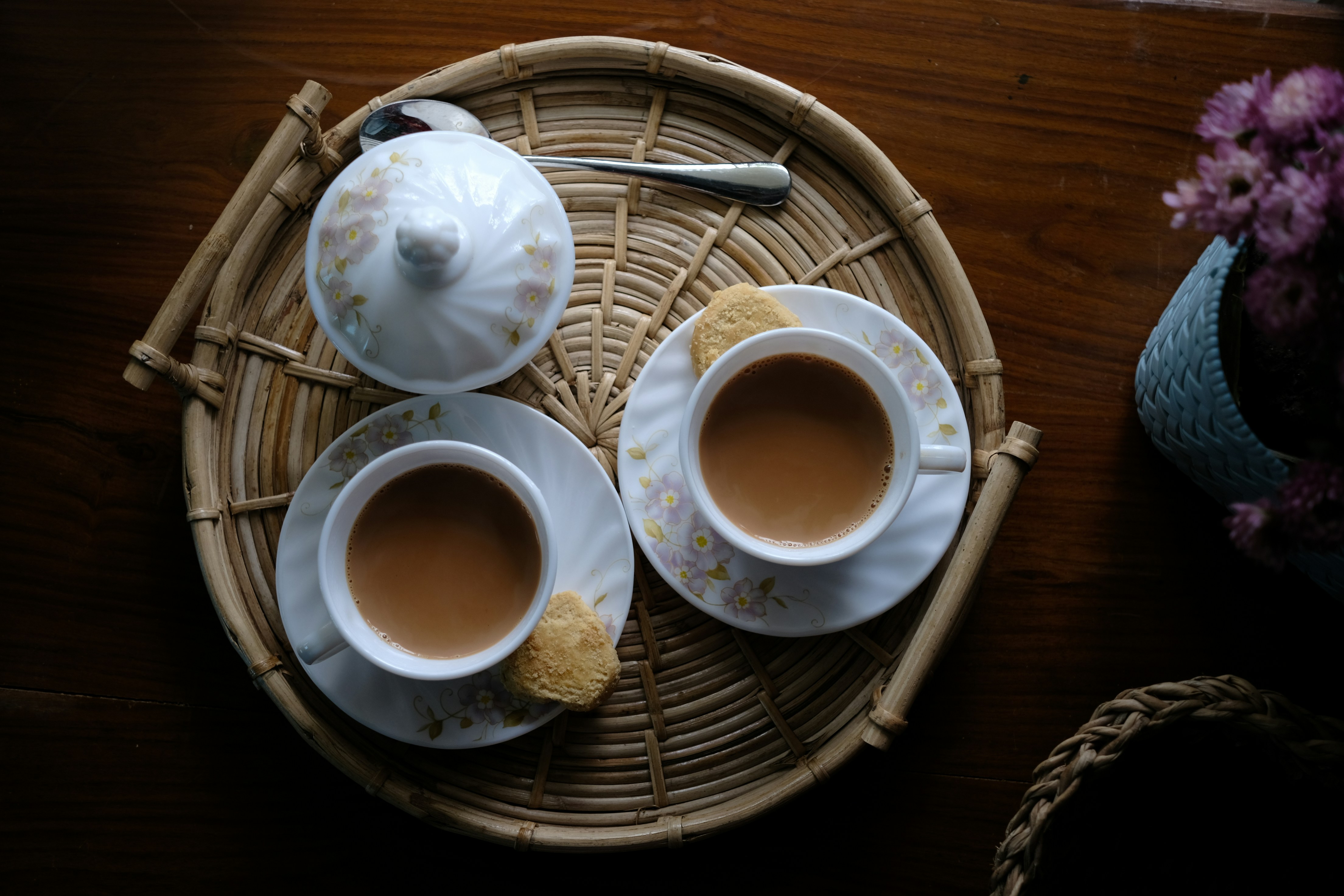 Two cups of coffee sitting on top of a wicker tray