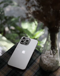 A cell phone sitting on top of a table next to a vase filled with flowers