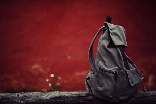A gray backpack sitting on top of a wooden bench