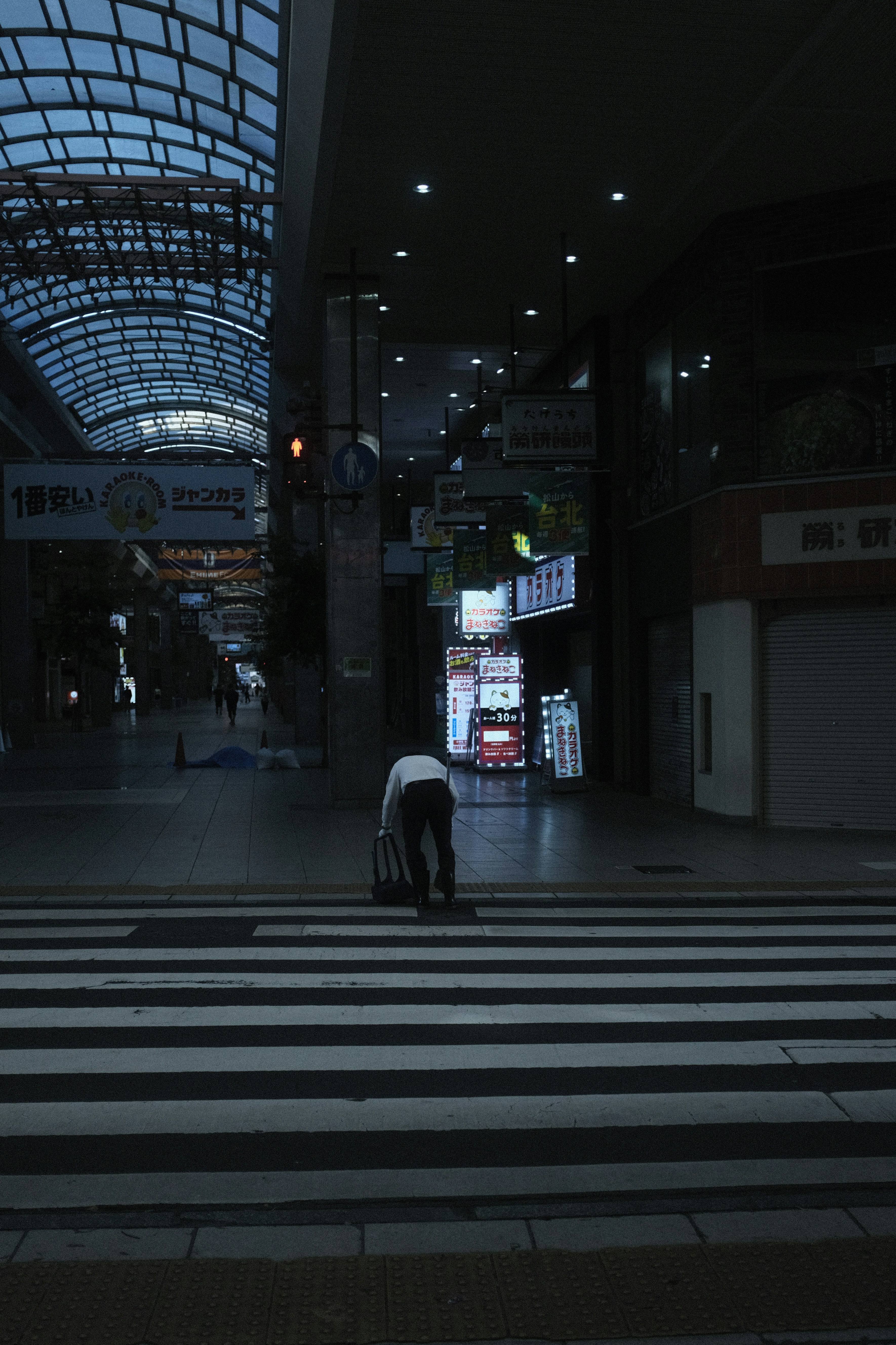 Eine Person mit einem Koffer, die mitten auf einem Zebrastreifen steht