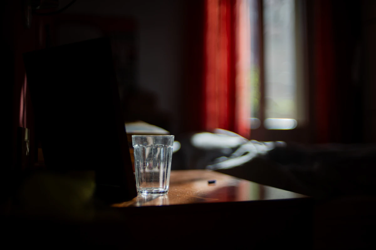 Wasserglas auf einem Tisch in einem dunklen Schlafzimmer
