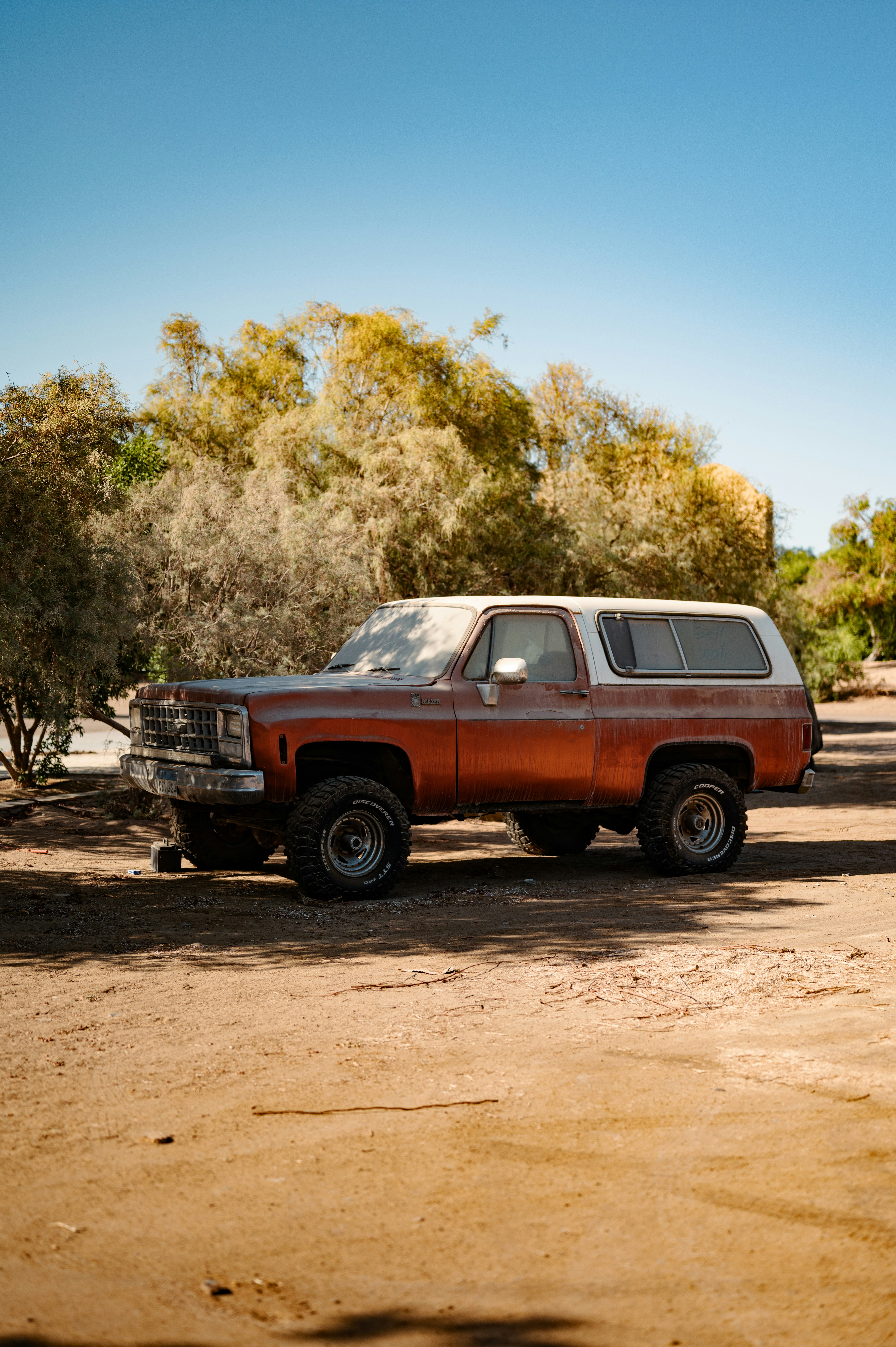 A brown truck parked in the middle of a dirt road