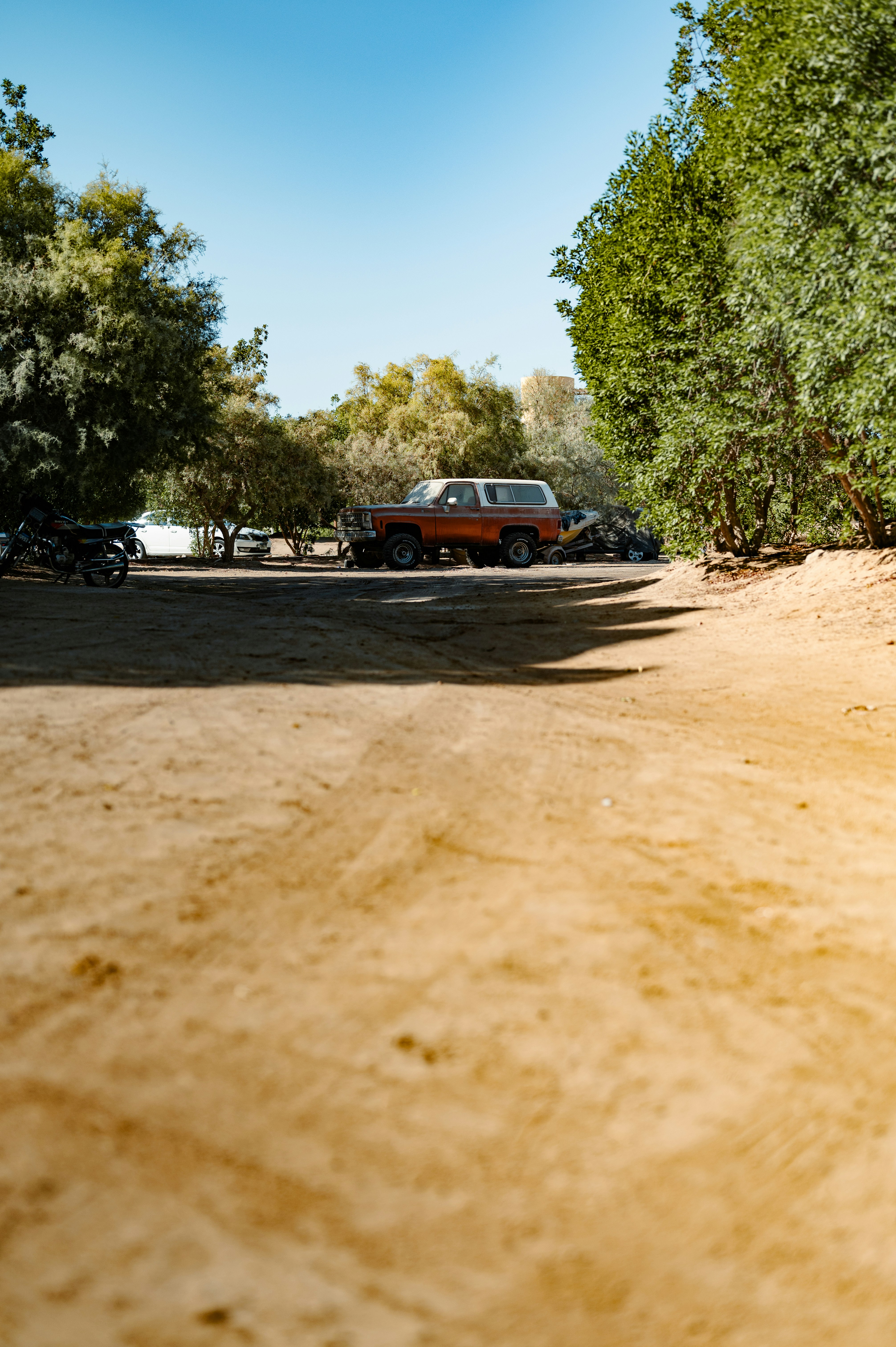 A dirt parking lot with cars parked on the side of it