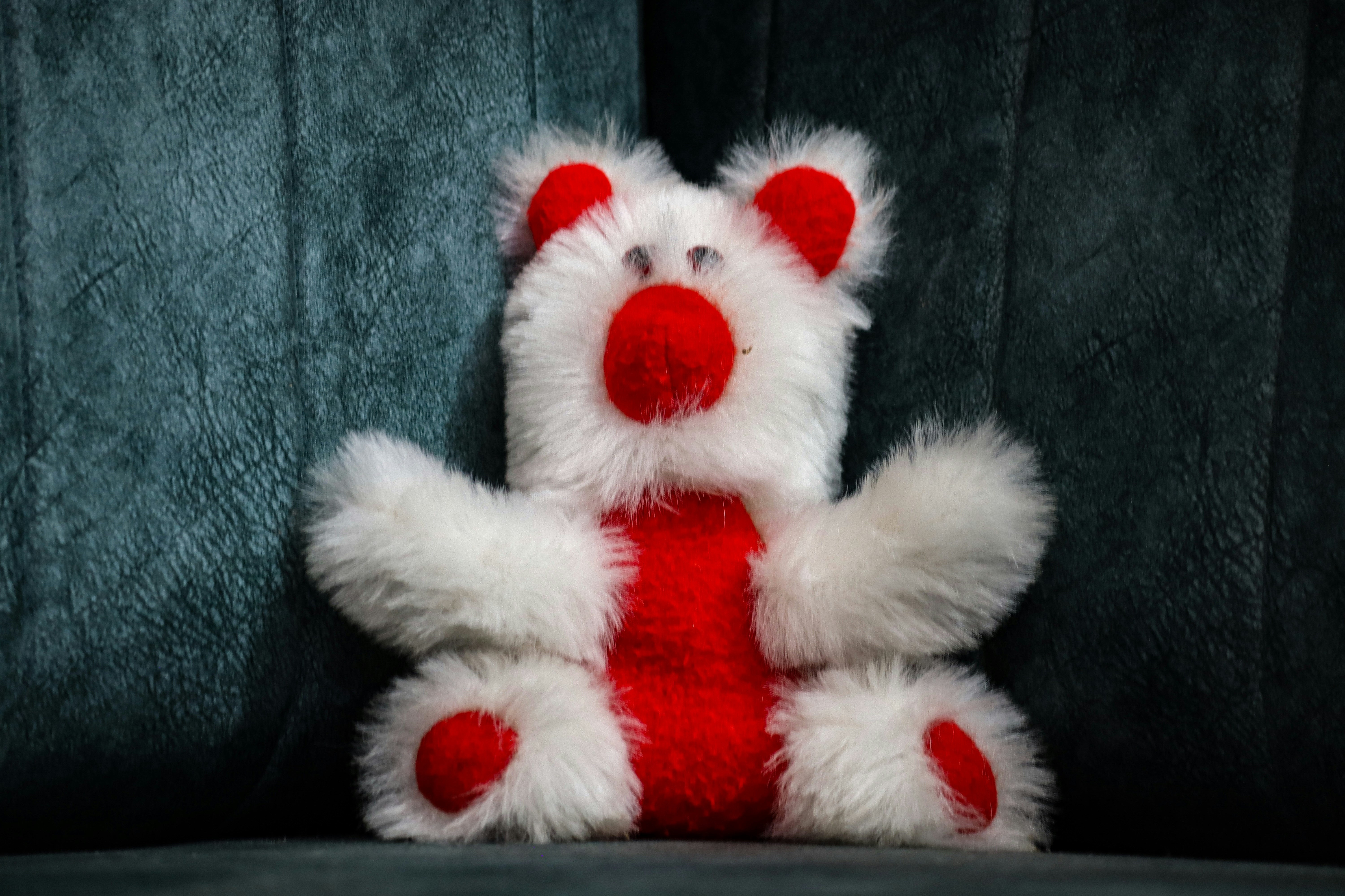 A white and red teddy bear sitting on a couch