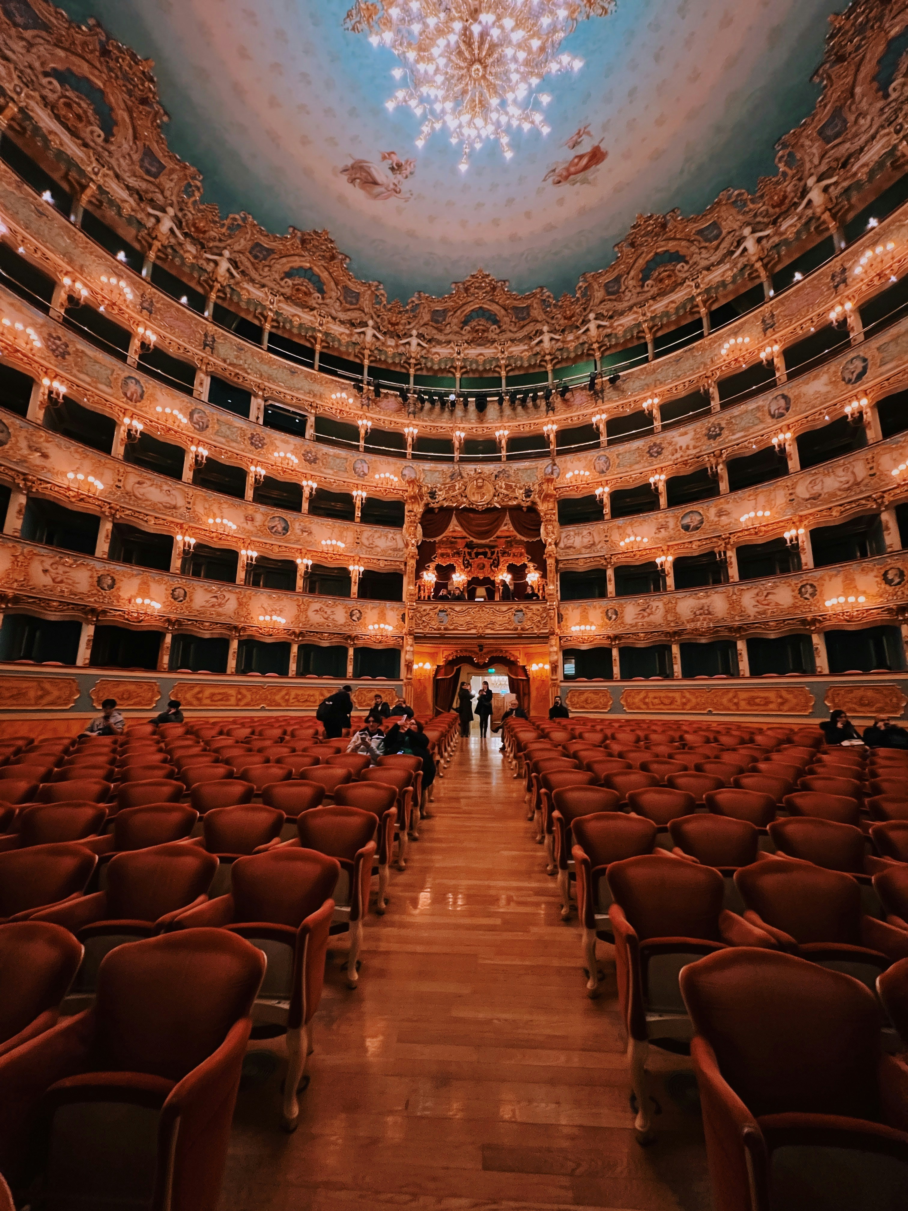 Notranjost Dubai Opera z elegantnimi sedeži in odrom med večerno predstavo
