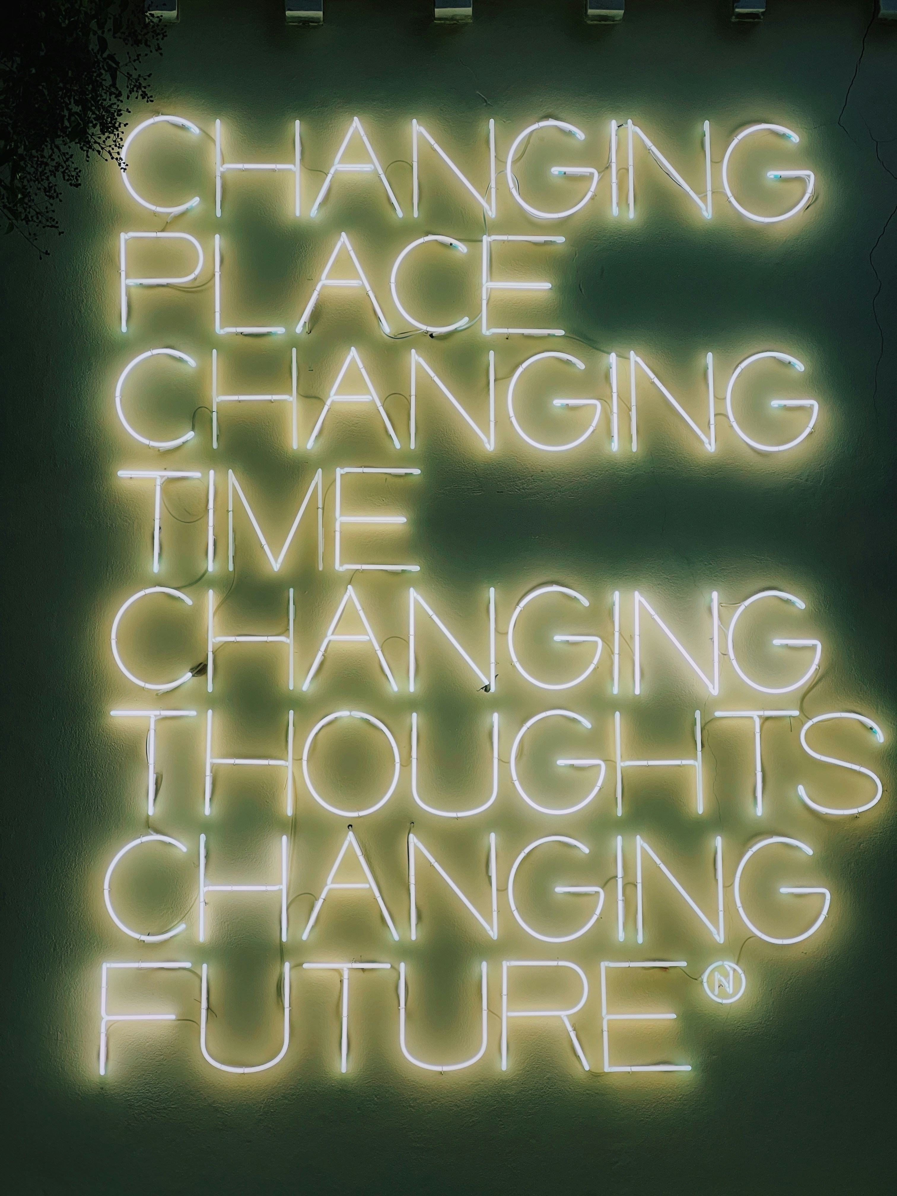 A neon sign that reads changing place changing time changing thoughts changing future