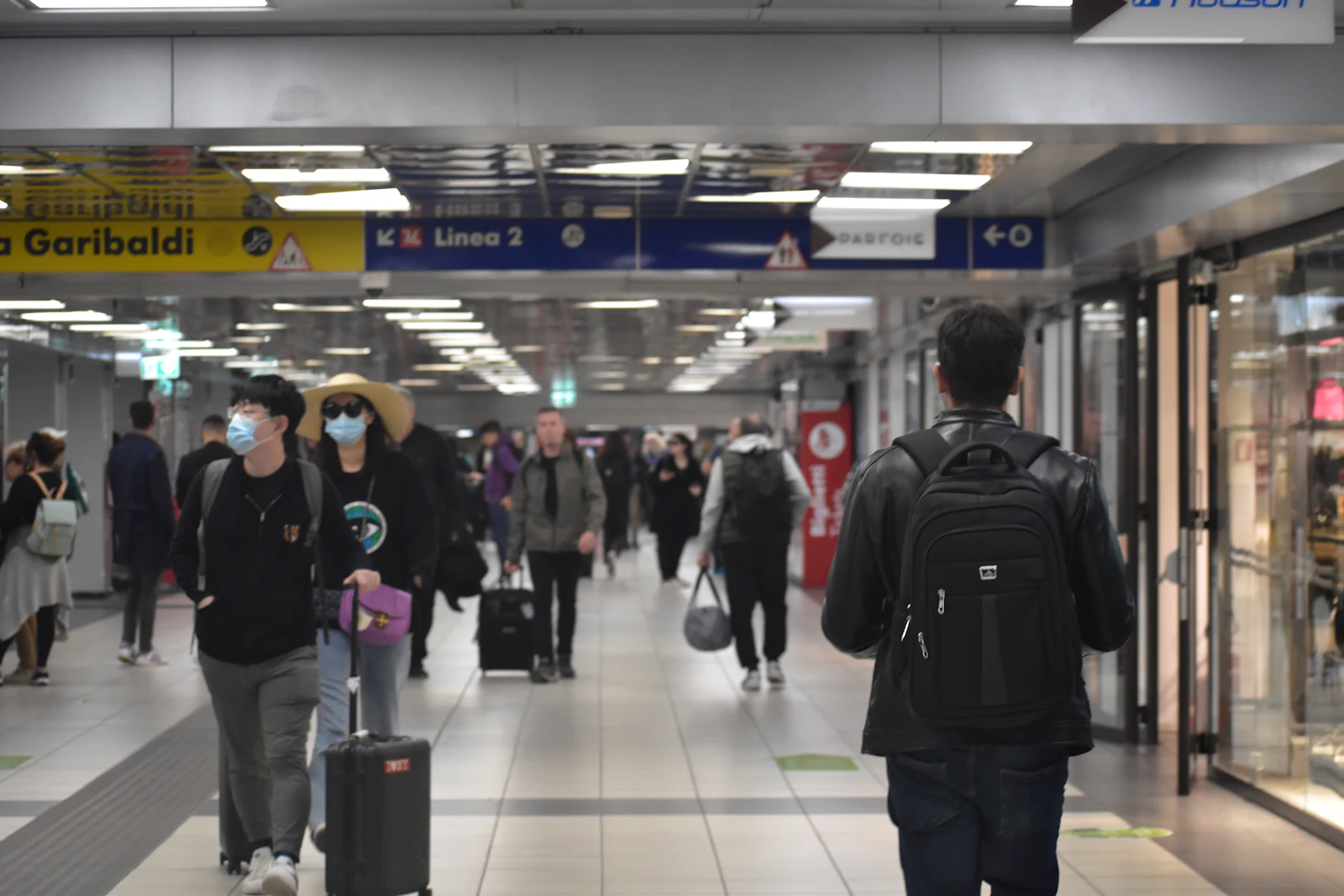Travellers with luggage walking through a busy train station in Italy