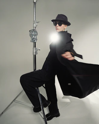 A man in a black suit and hat sitting on a chair