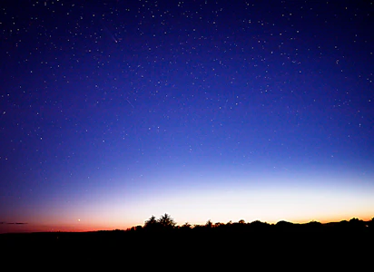 A night sky with stars and the moon in the distance