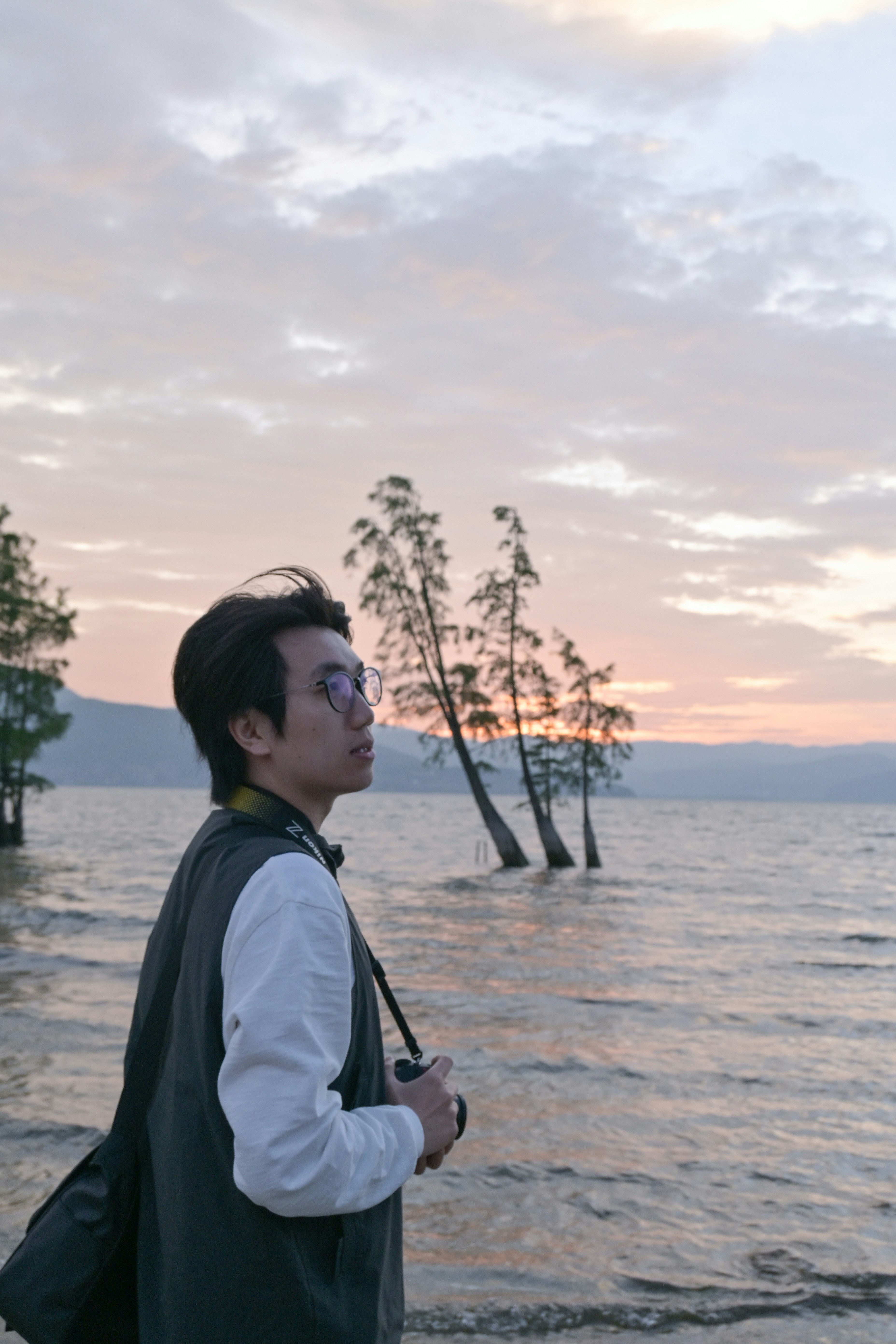 A man standing on a beach next to a body of water