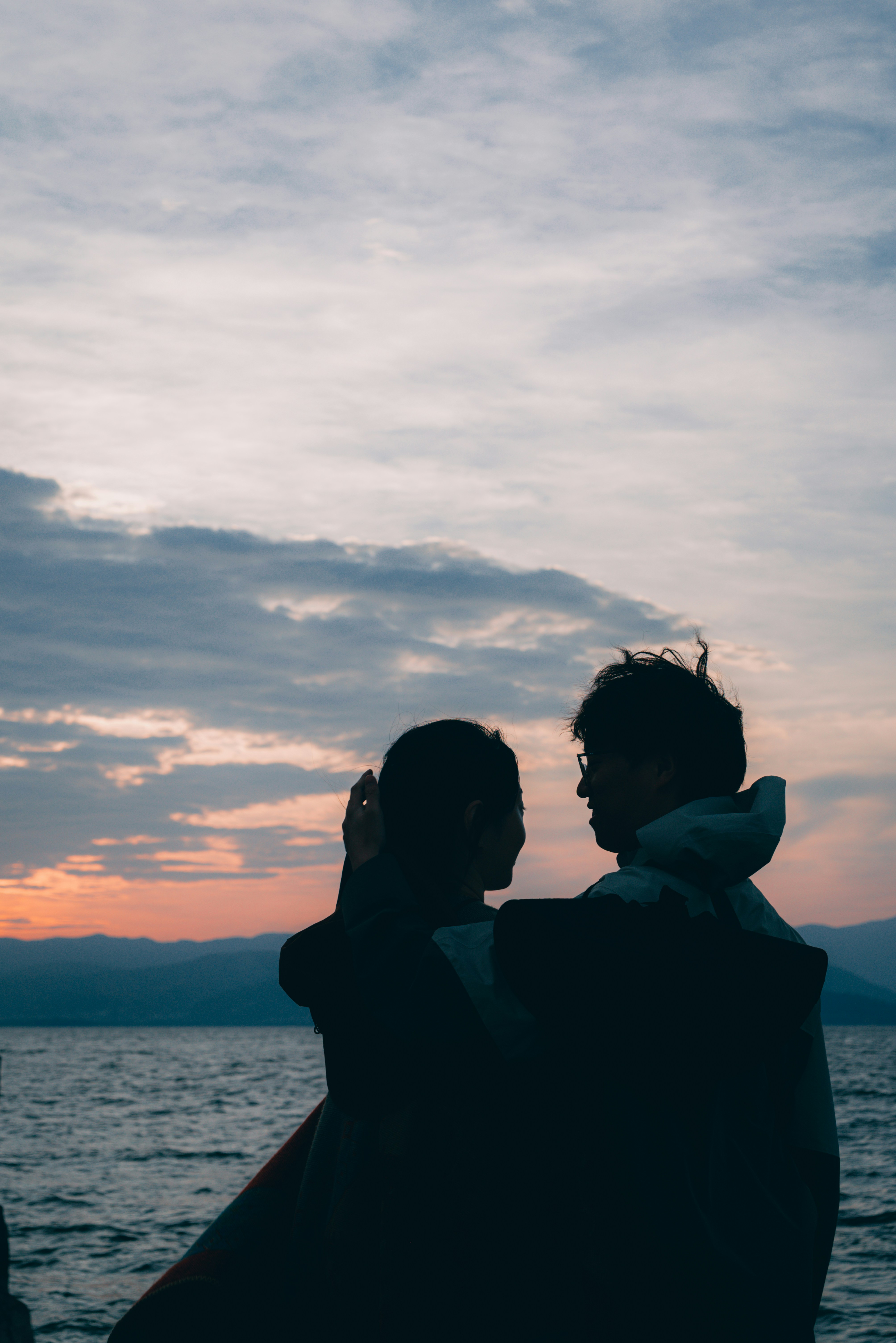 Two people standing next to each other near the water
