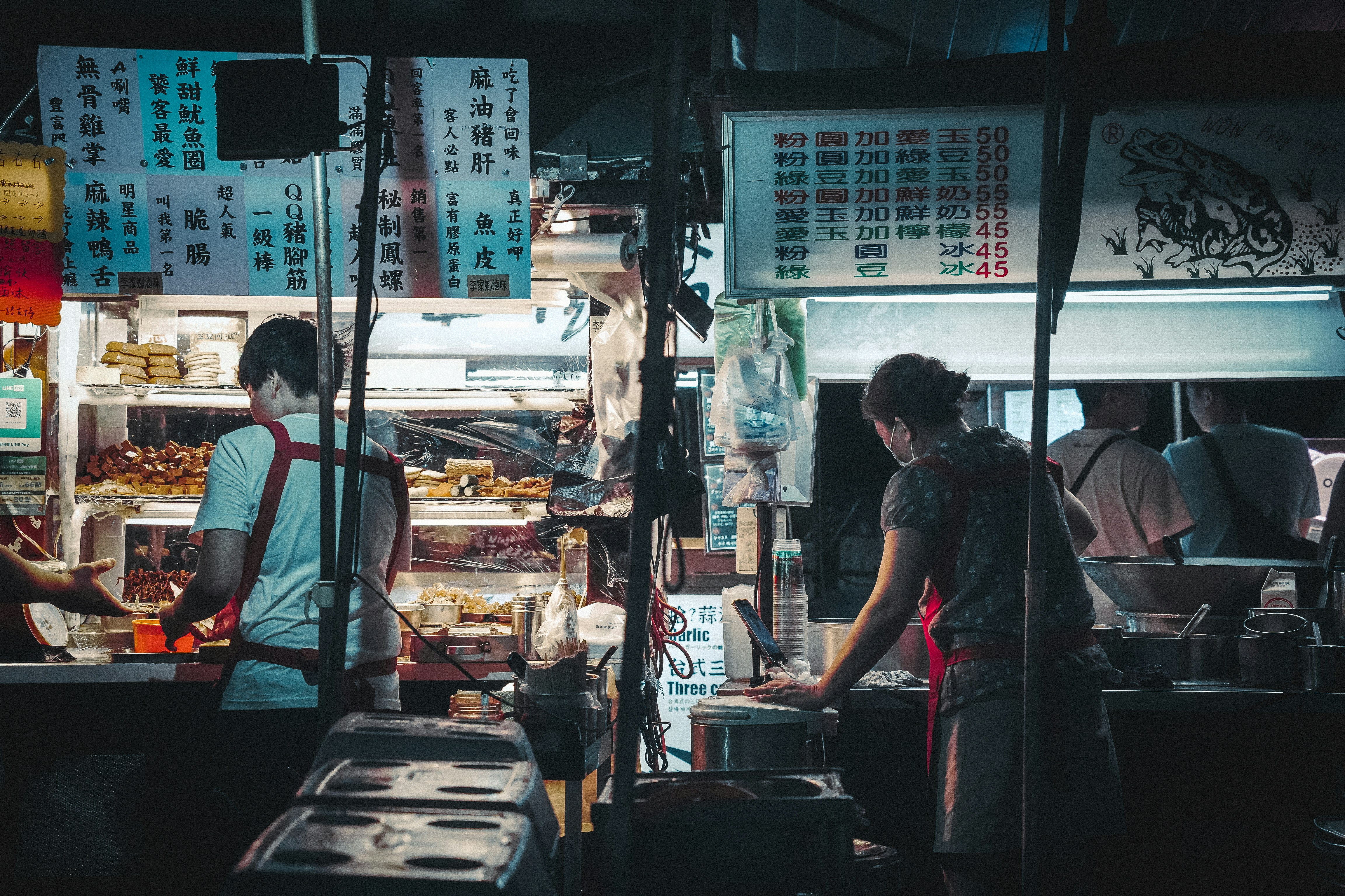 A group of people standing around a food stand, Taipei Night Food Market