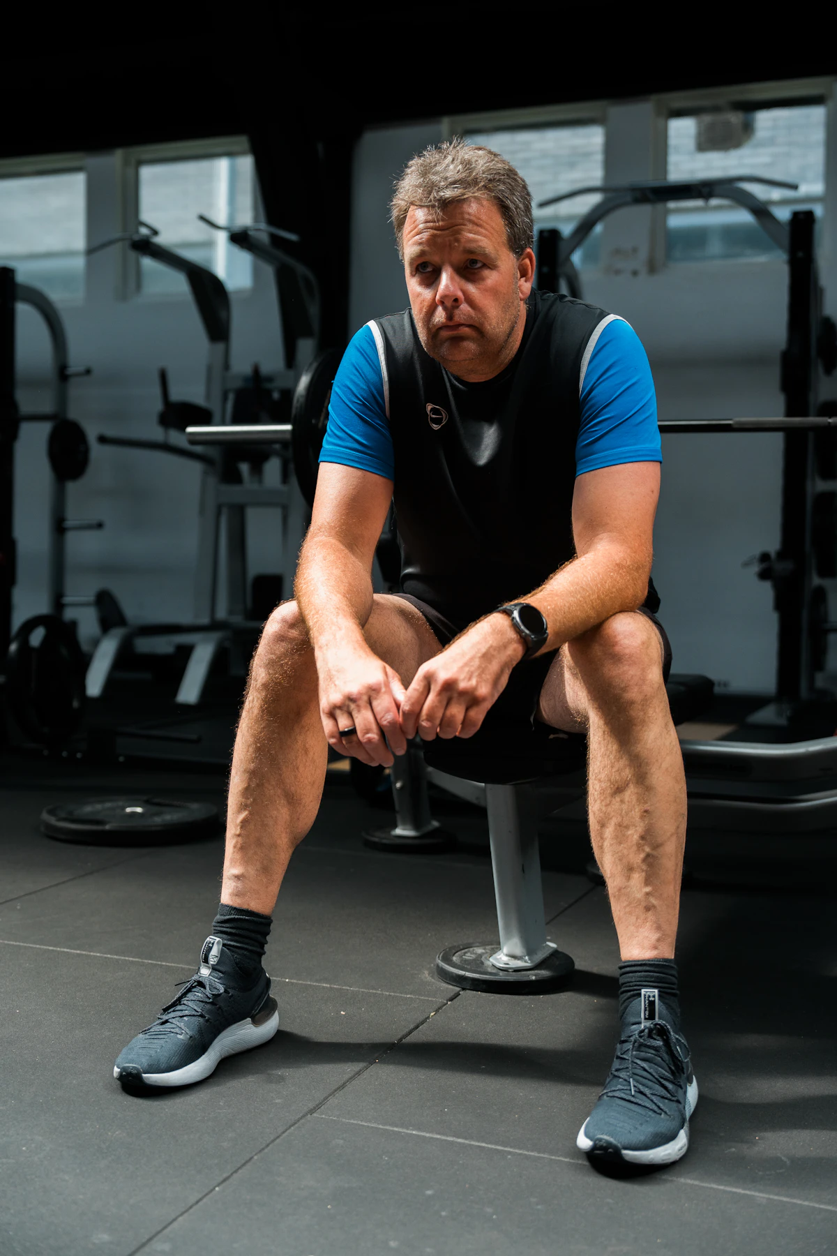 Man resting on a weight bench in a gym, illustrating how bone density and strength guide TRT dosing.