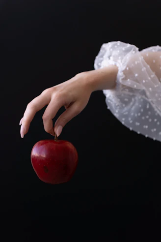 A woman in a white dress holding a red apple