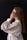 A woman in a white shirt is holding her hands to her face
