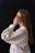 A woman in a white shirt is holding her hands to her face