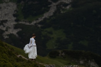 A woman in a white dress walking up a hill